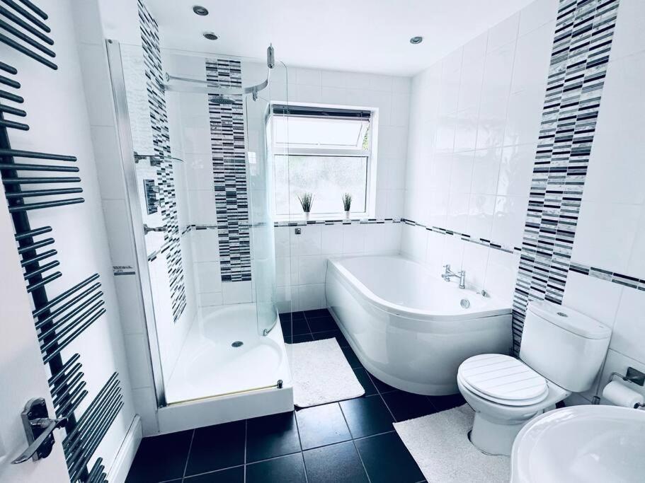 uma casa de banho branca com uma banheira, um WC e um lavatório. em Comfy House Near The City Centre em Nottingham
