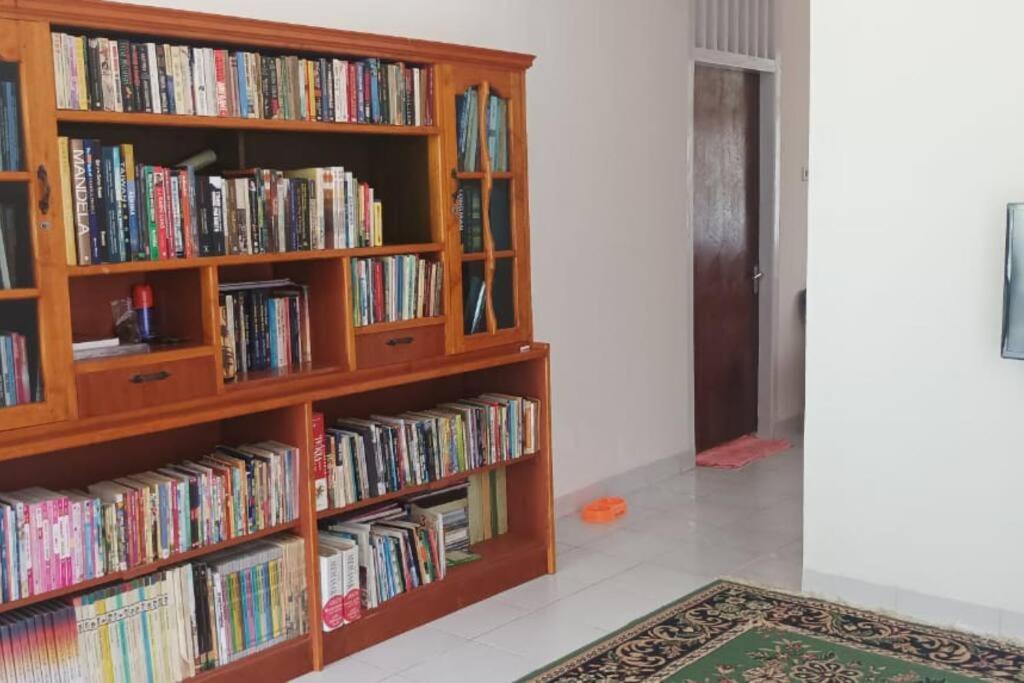 duas estantes de livros de madeira cheias de livros num quarto em Rumah Inyiak Aguang em Baso