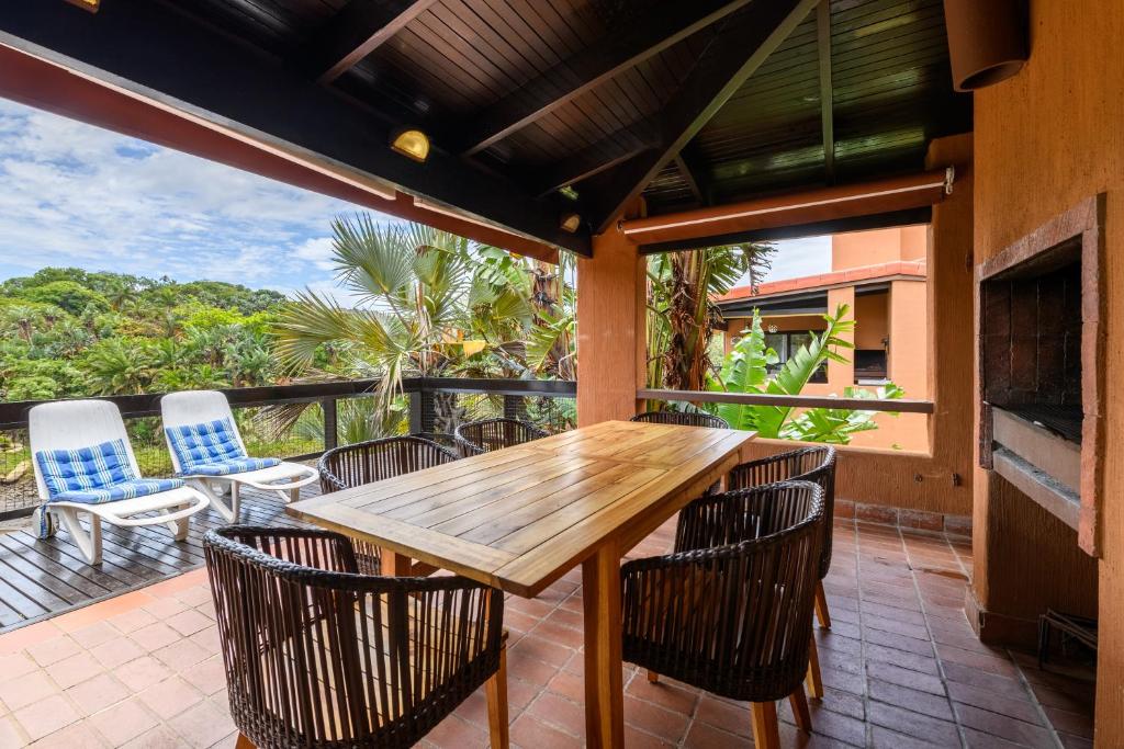an outdoor patio with a wooden table and chairs at San Lameer Villa 3108 - 4 Bedroom Classic - 8 pax - San Lameer Rental Agency in Southbroom