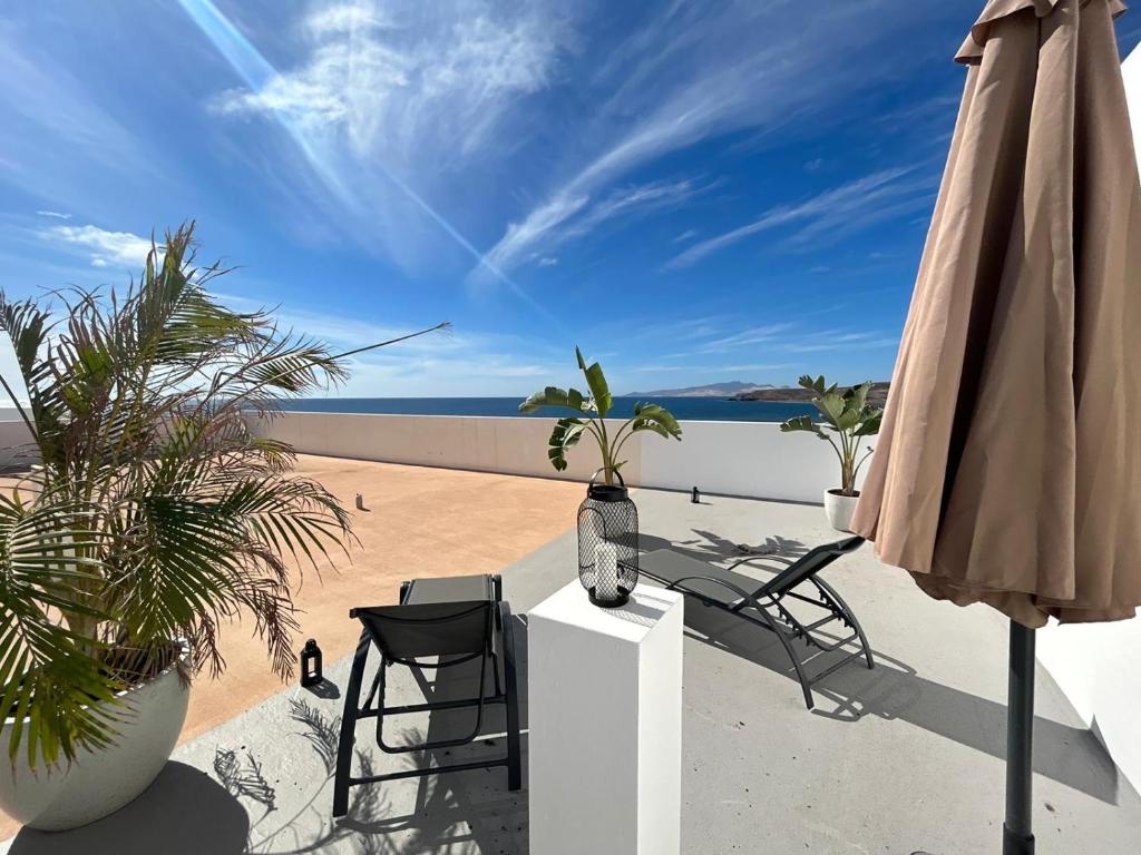 un patio con sillas y una sombrilla y la playa en Arte, en Tarajalejo