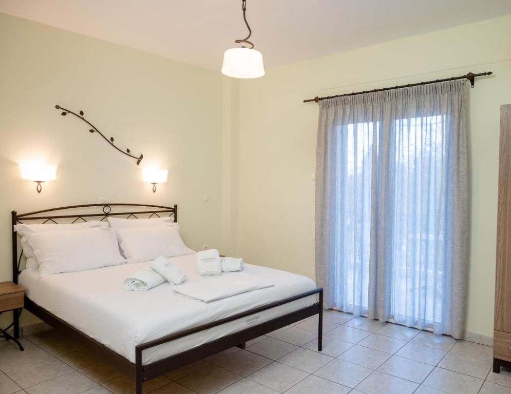 a bedroom with a bed with white sheets and a window at Konstantinos Hotel & Apartments 2 in Nydri