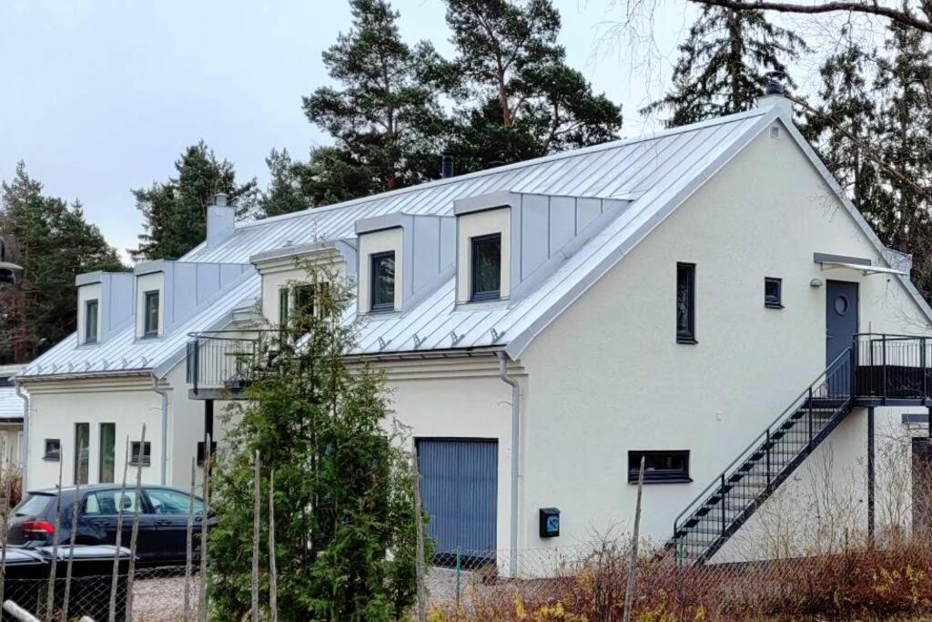 una casa blanca con techo de metal en Lägenhet i villa en Bålsta