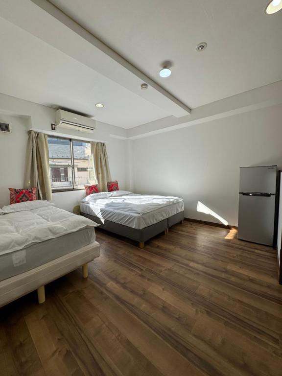 two beds in a room with wooden floors at PAThouse台东区店 in Tokyo