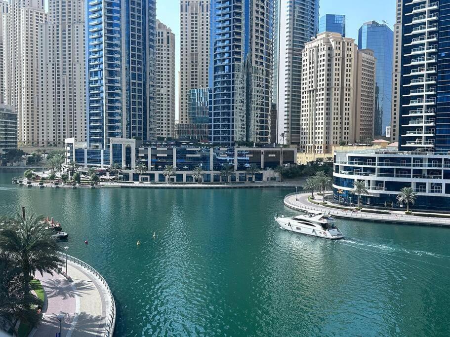 a boat in a river in a city with tall buildings at Tranquil Studio Marina View in Dubai