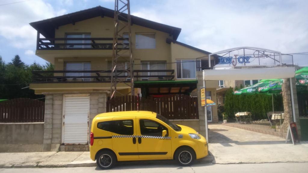 a small yellow car parked in front of a house at Enjoy Guest House in Golden Sands