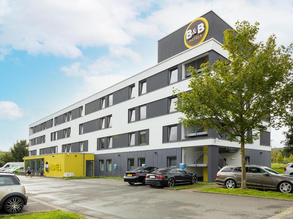 ein Bürogebäude mit auf einem Parkplatz geparkt in der Unterkunft B&B Hotel Düsseldorf-Airport in Düsseldorf
