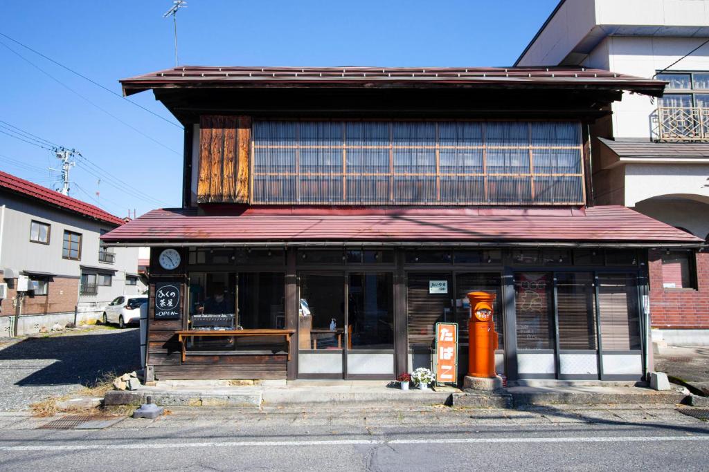 a building with an orange fire hydrant in front of it at GLOCE西会津 ふくの屋 l 古きを知り新しきを愉しむ l 築110年超の古民家が綴る心地よい宿 in Yanaizu