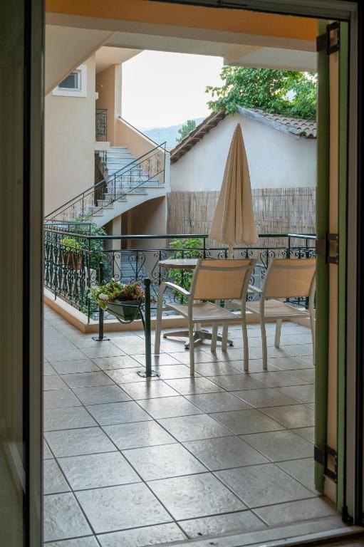 a balcony with a table and chairs and a umbrella at Konstantinos Hotel & Apartments 2 in Nydri