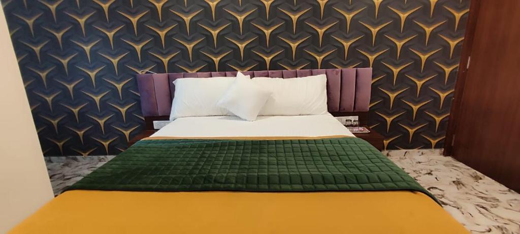 Hotel Shaswat Inn في أحمد آباد: غرفة نوم بسرير وبطانية خضراء وصفراء
