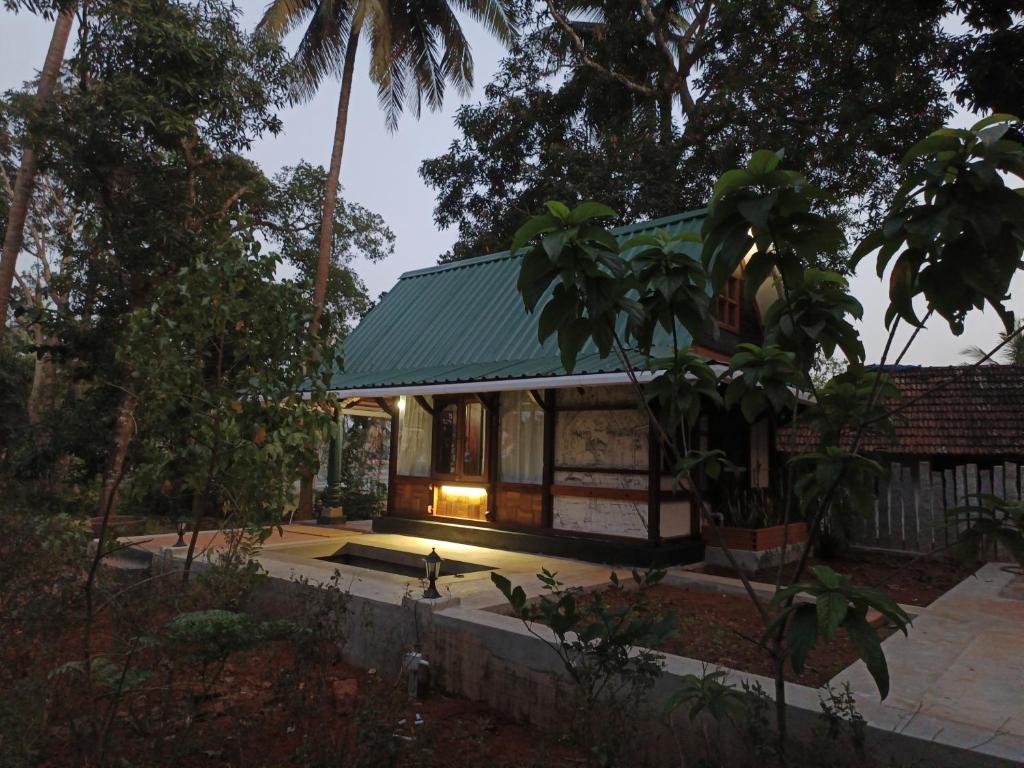 a house with a green roof in the middle of trees at Svarna in Udupi