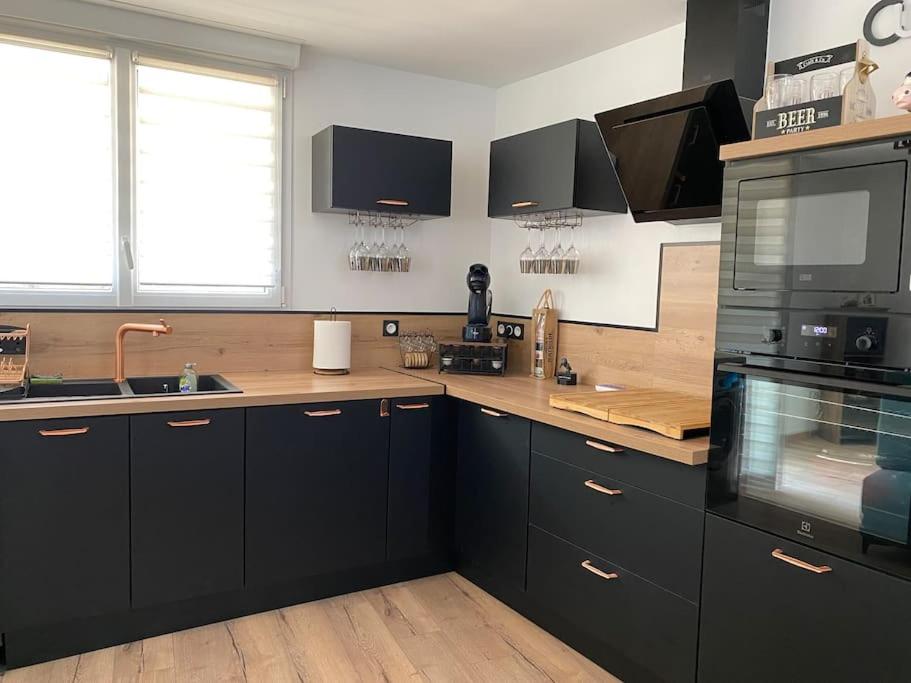 a kitchen with black cabinets and a stove top oven at Superbe Appartement atypique in Bouleternère