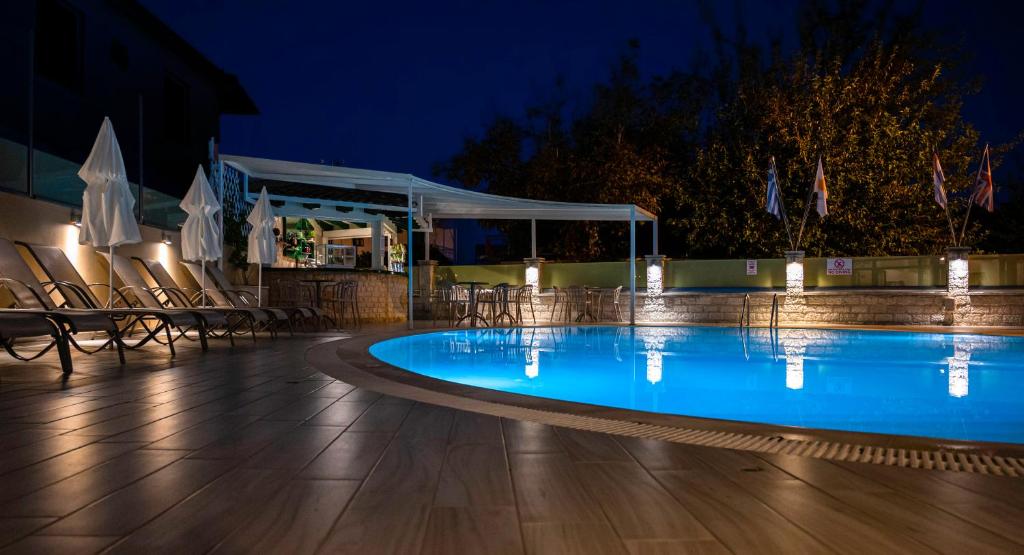a swimming pool at night with chairs and umbrellas at Konstantinos Hotel & Apartments 2 in Nydri