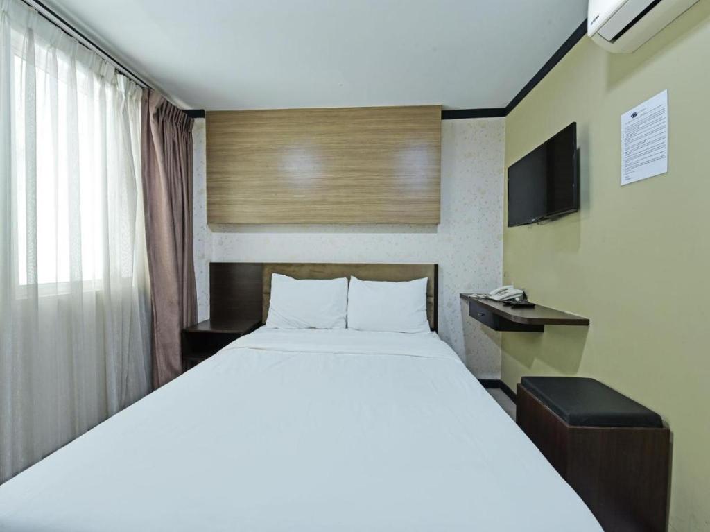 um quarto com uma grande cama branca e uma televisão em One Enigma Hotel em Kuala Lumpur