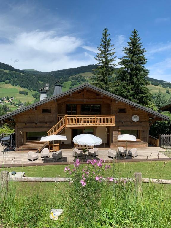 a large wooden building with chairs and tables in front of it at Chalet haut de gamme Fleurs des Bois in Megève