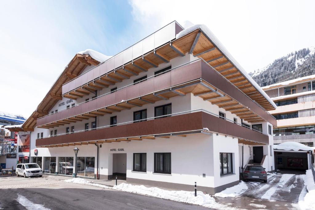a building in a parking lot with snow on the ground at Hotel Gabl by Alpeffect Hotels in Sankt Anton am Arlberg
