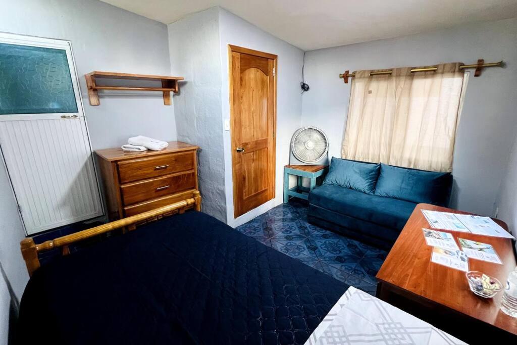Habitación pequeña con sofá azul y mesa. en Cómoda habitación privada 2 personas FULL BED & FULL SOFA CAMA en Puerto Ayora