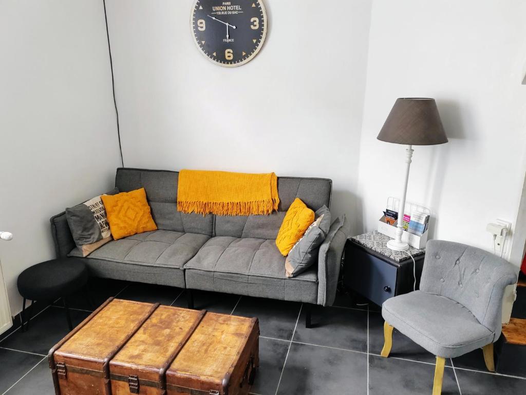 a living room with a couch and a clock on the wall at LA PETITE MAISON in Beauvais
