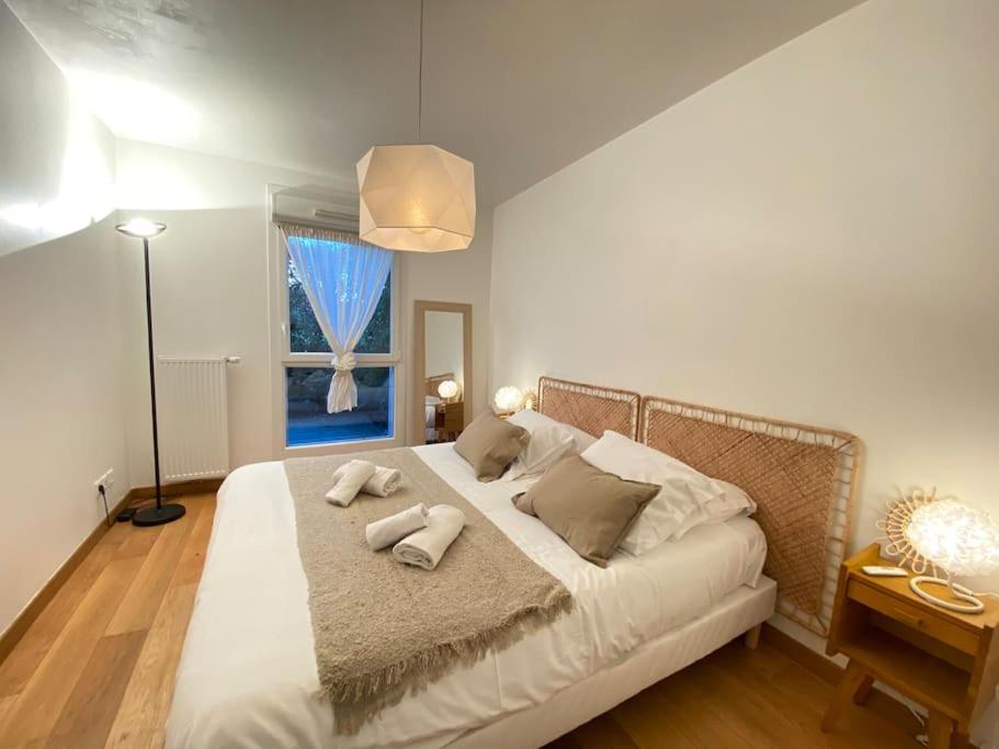 una camera da letto con un letto bianco e asciugamani di Maïs Cottage, terrasse ensoleillée avec vue ! ad Annecy