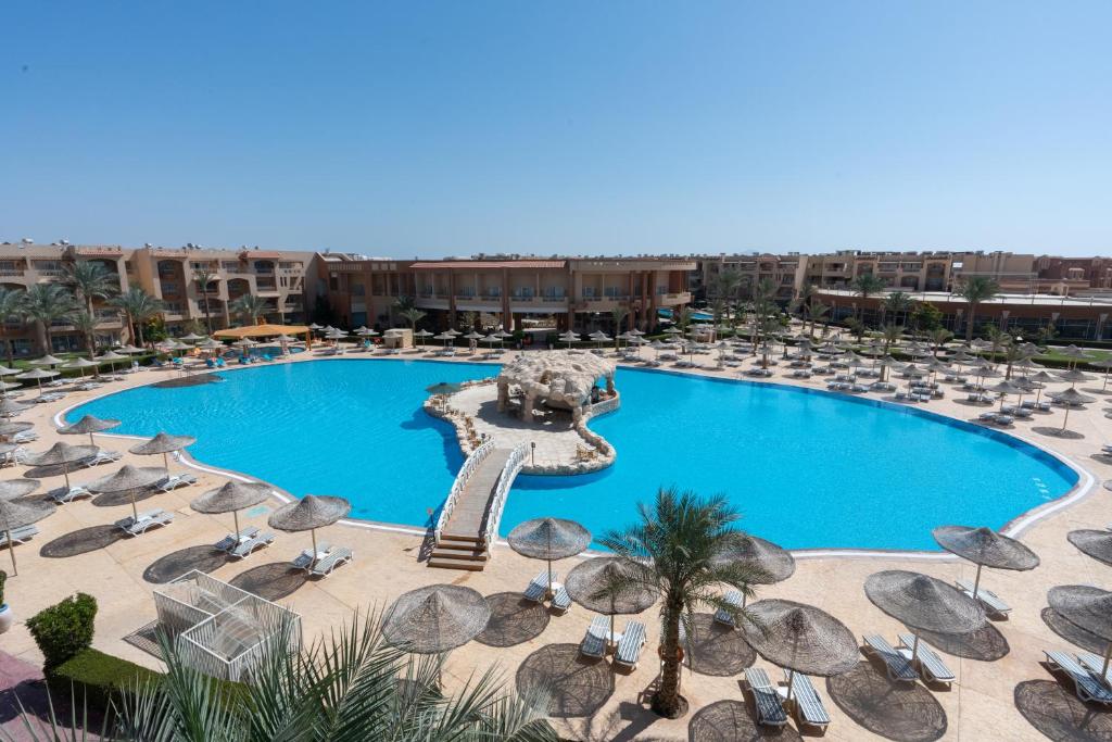 a pool with chairs and umbrellas in a resort at Parrotel Lagoon Waterpark Resort in Sharm El Sheikh