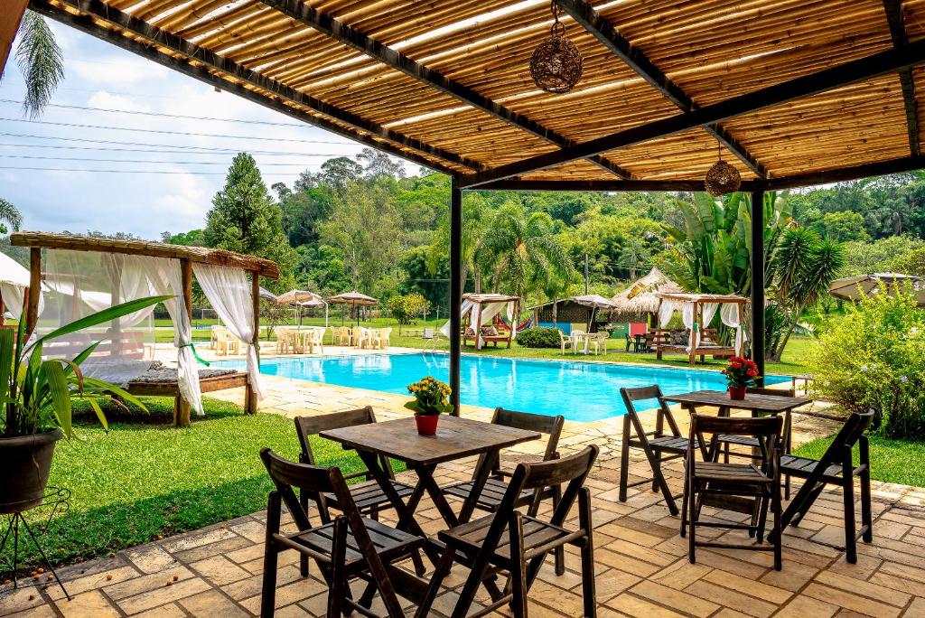 un patio con mesas y sillas junto a una piscina en Estância Canaã Atibaia, en Atibaia
