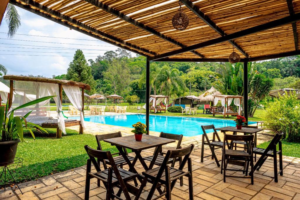 a patio with tables and chairs next to a pool at Estância Canaã Atibaia in Atibaia