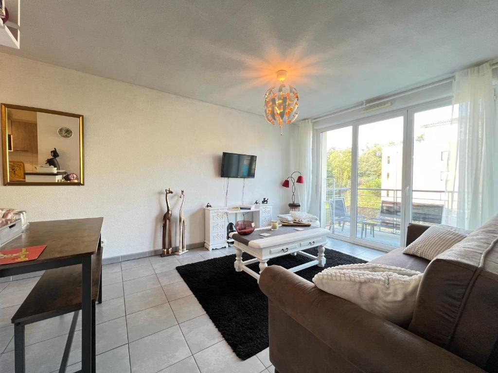 a living room with a couch and a table at Mon Cocon Occitan - 2p - Wifi &amp; Parking in Colomiers