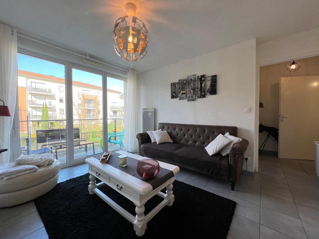 a living room with a couch and a table at Mon Cocon Occitan - 2p - Wifi &amp; Parking in Colomiers