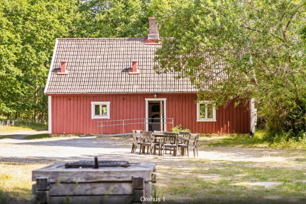 ein rotes Haus mit einem Tisch und Stühlen davor in der Unterkunft Orehus - Country side cottage with garden in Sjöbo