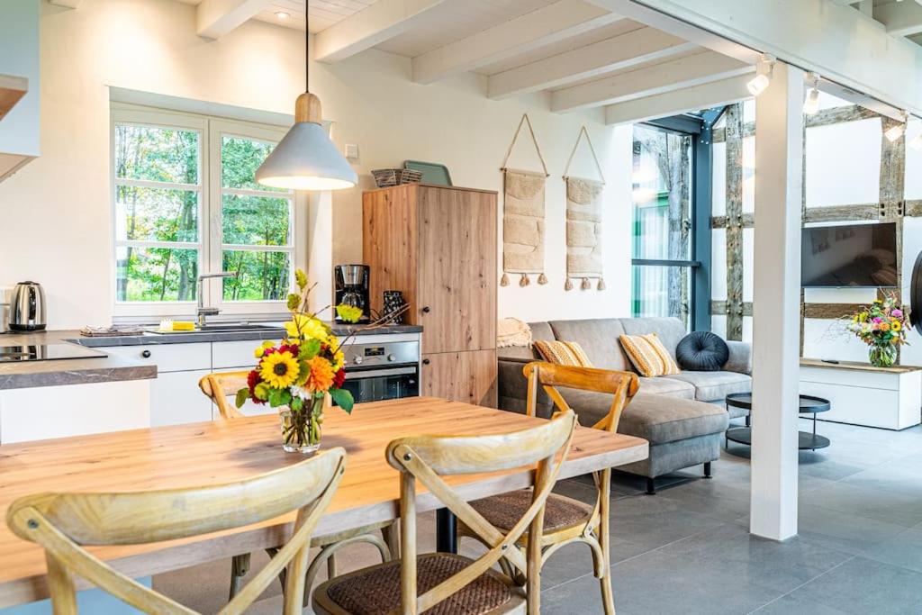kuchnia i salon z drewnianym stołem i krzesłami w obiekcie Ferienwohnung "Stellmacherei" w mieście Versmold
