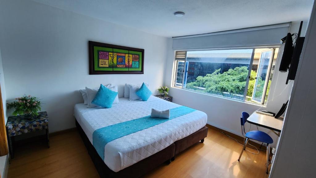Un dormitorio con una cama con almohadas azules y una ventana en Hotel Blue Zafiro, en Bogotá