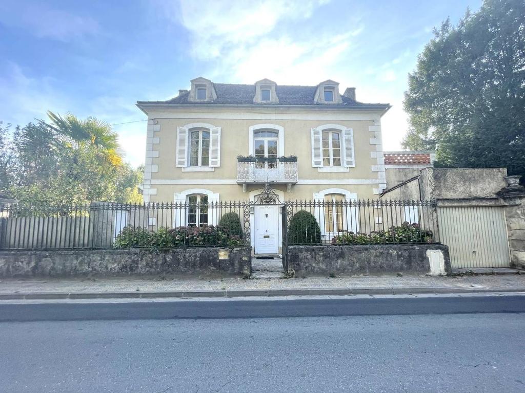 ein großes gelbes Haus mit einem Zaun davor in der Unterkunft Au bord de la Vézère in Le Bugue