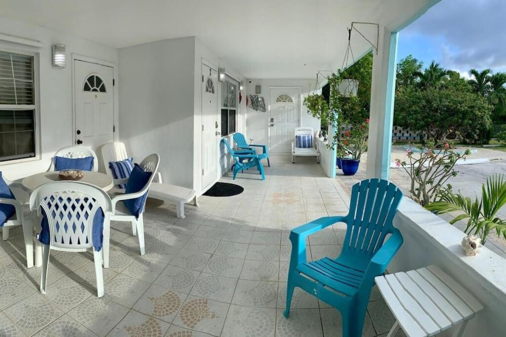 a patio with blue chairs and a table on a porch at SUITE 2, BLUE PAVILION - Steps to BEACH in West Bay