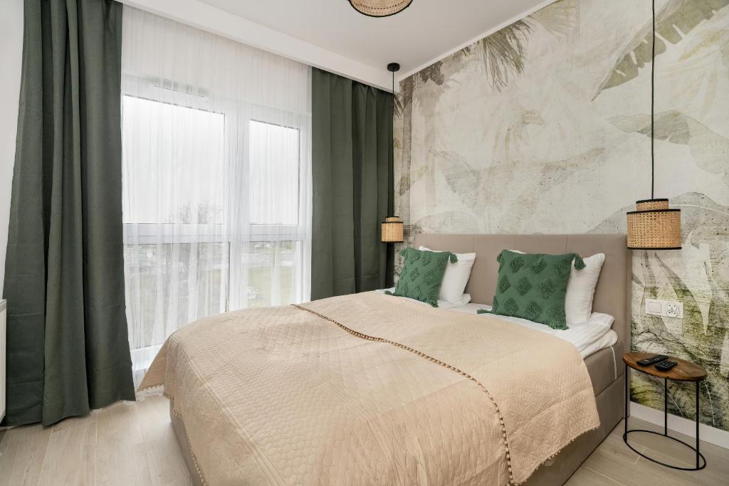 1 dormitorio con 1 cama grande y 2 almohadas verdes en Tasteful Beige Apartment with Parking by Renters en Poznan