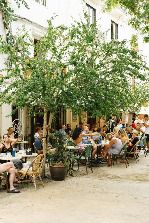 a group of people sitting at tables in an outdoor restaurant at 7Pines Resort Ibiza, part of Destination by Hyatt in San Jose