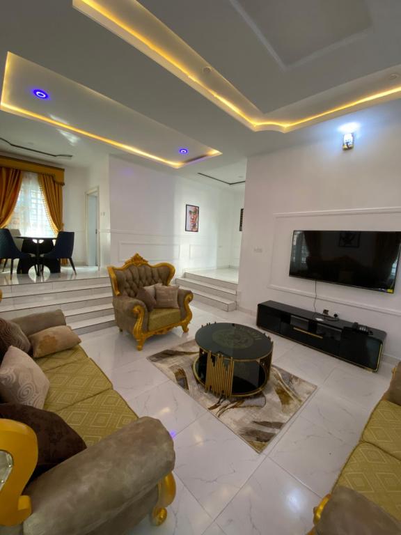 a living room with a couch and a tv and a table at MilesVilla Apartments in Enugu
