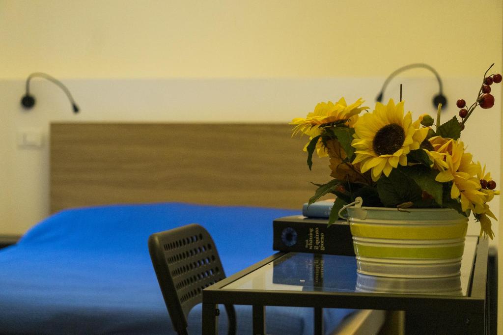 a vase of sunflowers on a table with a bed at Tenute Valerio 