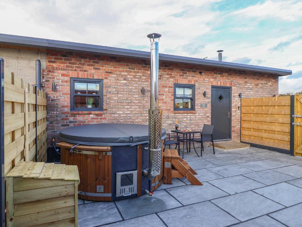 a hot tub on a patio next to a brick building at Robins Nest in York