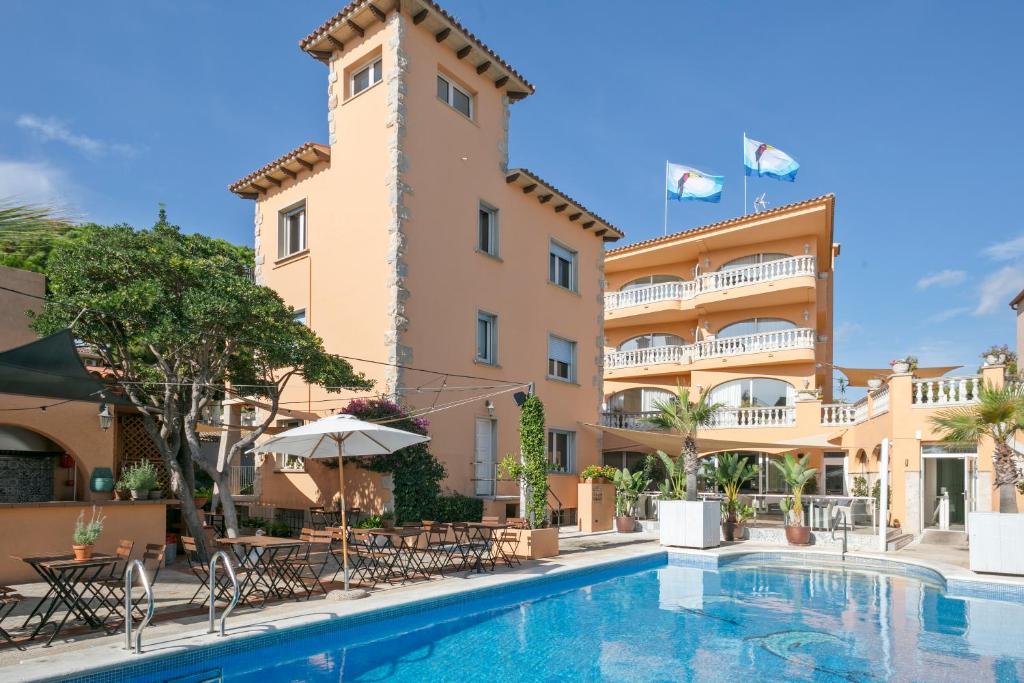 un hotel con piscina frente a un edificio en Van der Valk Hotel Barcarola en Sant Feliu de Guixols