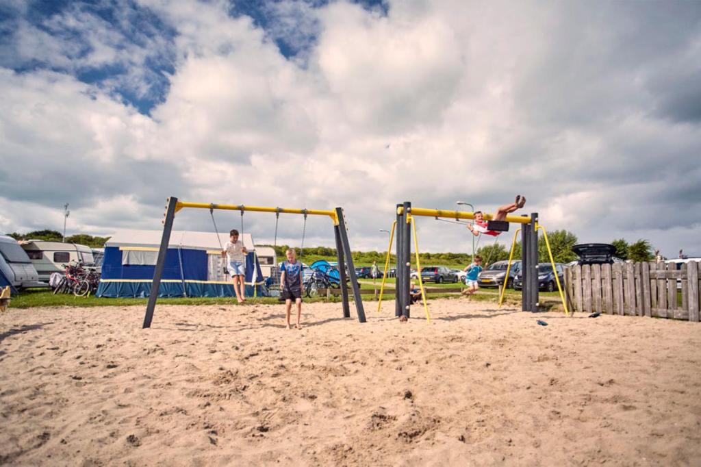 2 bambini che giocano su un'altalena sulla spiaggia di Strandcamping Jagtveld a 's-Gravenzande