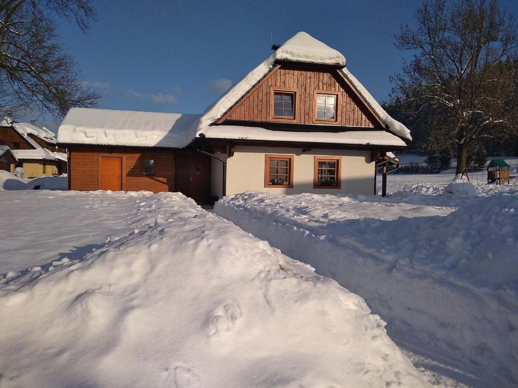a house with a pile of snow in front of it at Valachy chalupa Velké Karlovice in Velké Karlovice