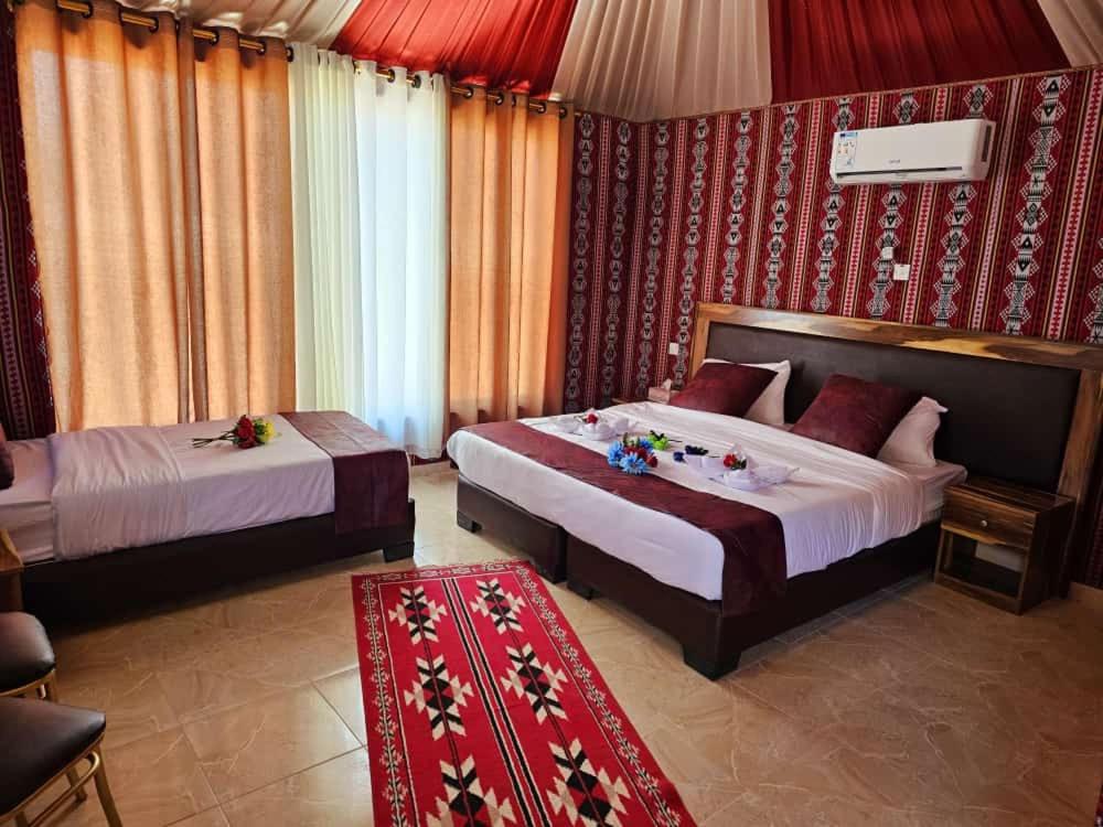 a bedroom with two beds and a red wall at Harir Rum luxury camp in Wadi Rum