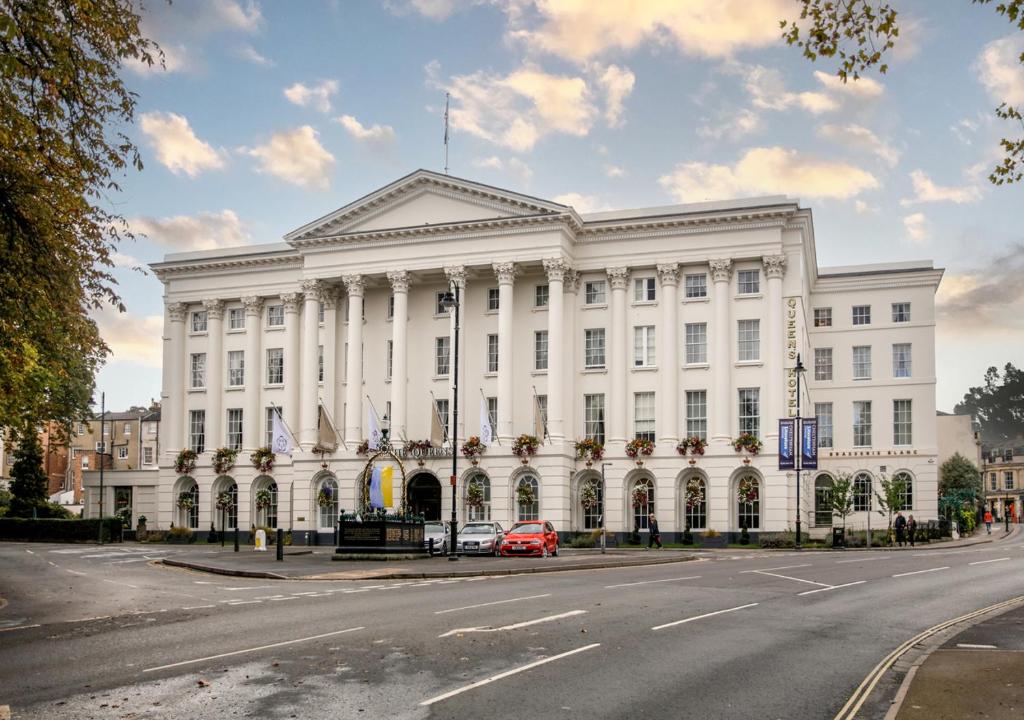 Queens Hotel Cheltenham في تشلتنهام: مبنى ابيض امامه سيارة حمراء