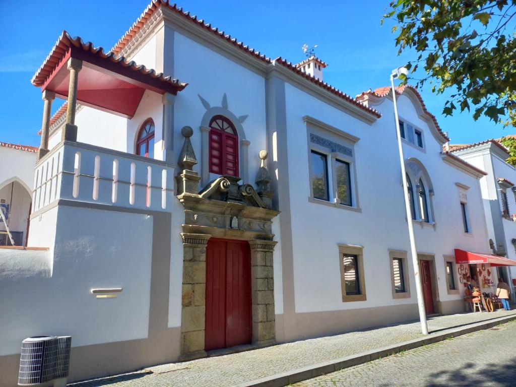 a white building with a red door on a street at CASA DA ALAMEDA in Nisa