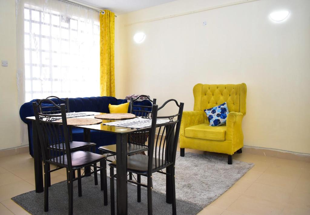 comedor con mesa, sillas y silla amarilla en Faisha 1bedroom Near Sarova Woodlands, en Nakuru