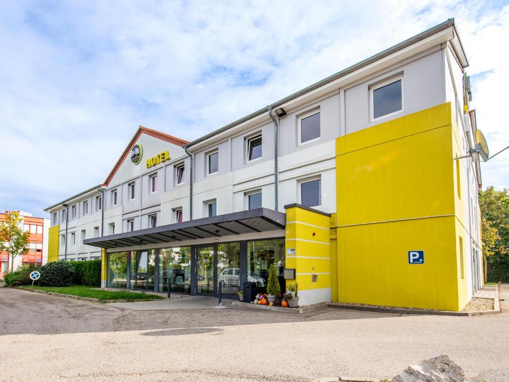 un hôtel avec un bâtiment jaune et blanc dans l'établissement B&B Hotel Ingolstadt, à Ingolstadt