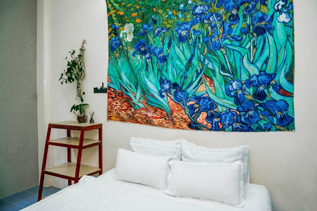 uma pintura na parede acima de uma cama num quarto em Bụi Hostel - Bến Tàu Rạch Giá em Rạch Giá