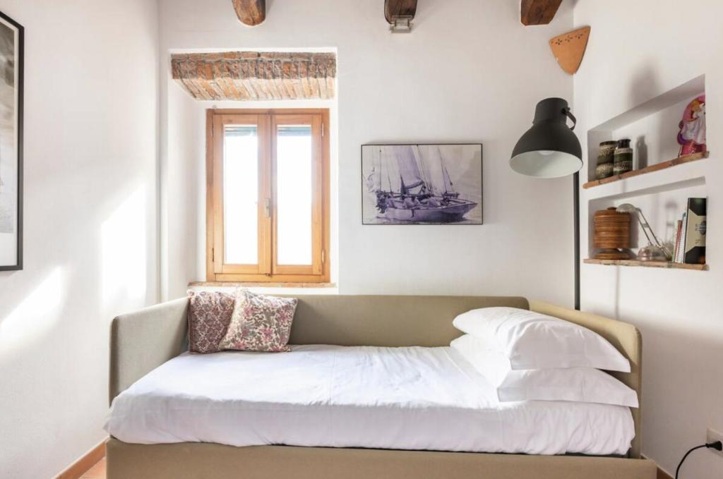 a bed with white sheets and a window in a room at Vuotopieno Casa Blue Maremma in Orbetello