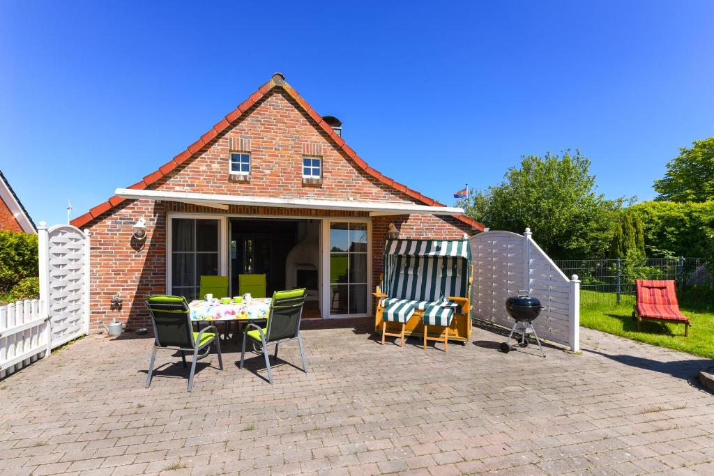 a patio with a table and chairs and a grill at Ferienhaus Sternenklar in Wittmund