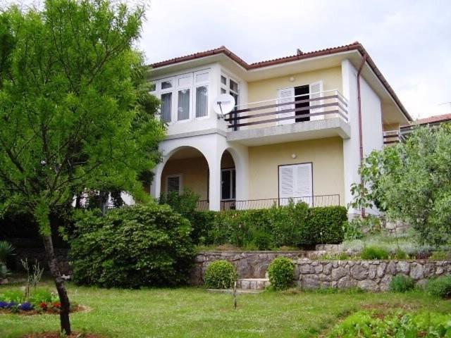 a large white house with a stone wall at Apartment Jasenka in Krk