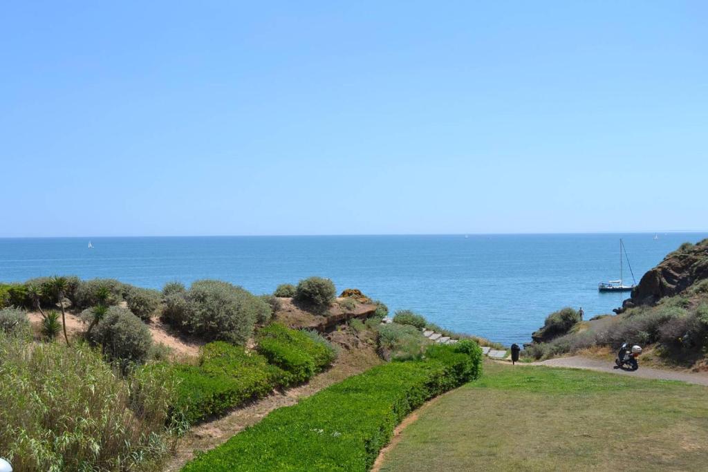 un chemin au bord de l'océan avec un bateau au loin dans l'établissement 060 Jardin de la Conque B13, au Cap d'Agde
